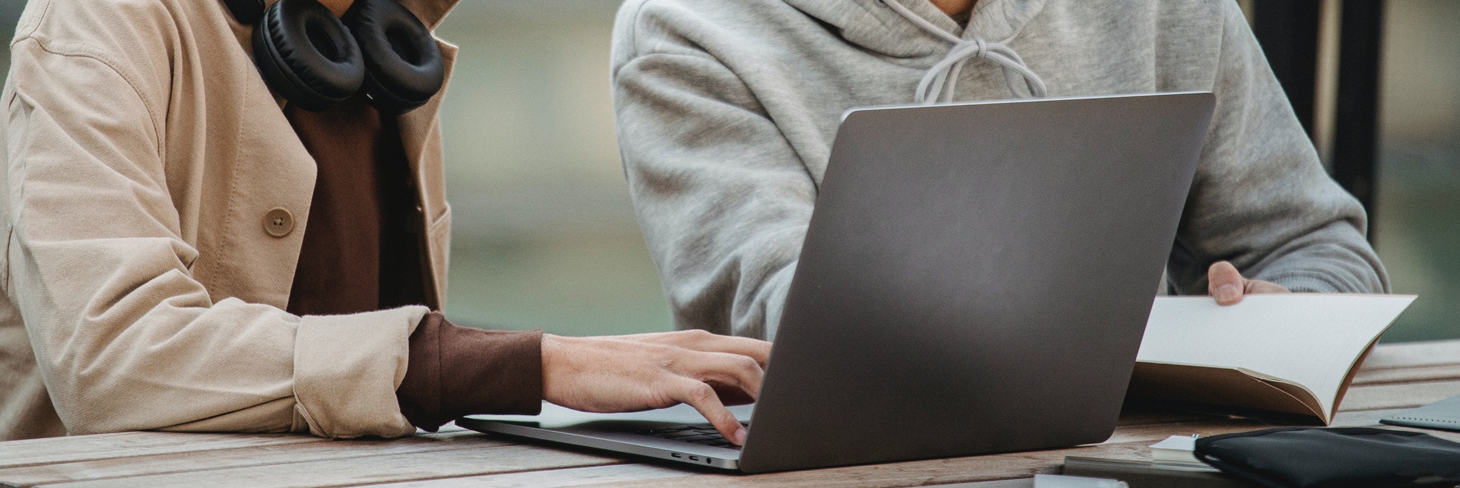 Closeup of a laptop and two people sitting behind it